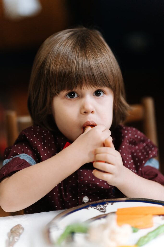 girl in red and white polka dot shirt sitting on chair eating food