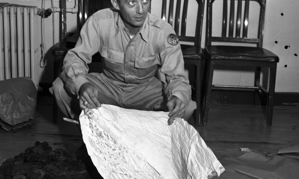 a man sitting on the floor holding a foil object. Roswell Incident