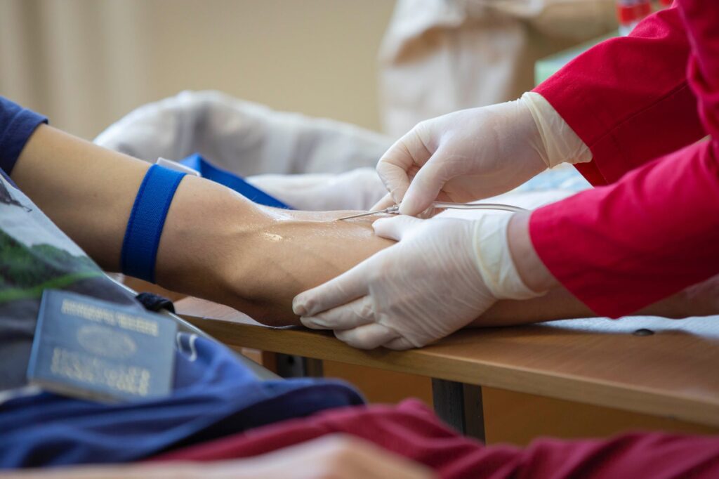 a medical professional inserting needle to s person s arm. World Blood Donor Day