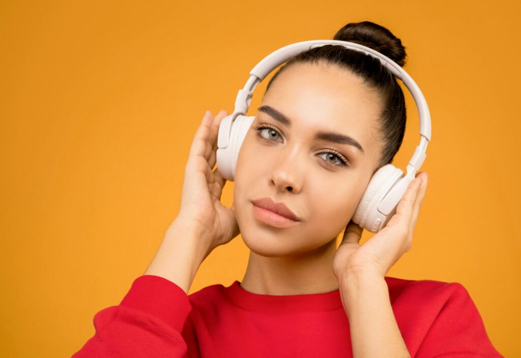 photo of woman wearing white headphones. "Image: Spotify logo with a price tag overlay, representing the price increase for their music download services."