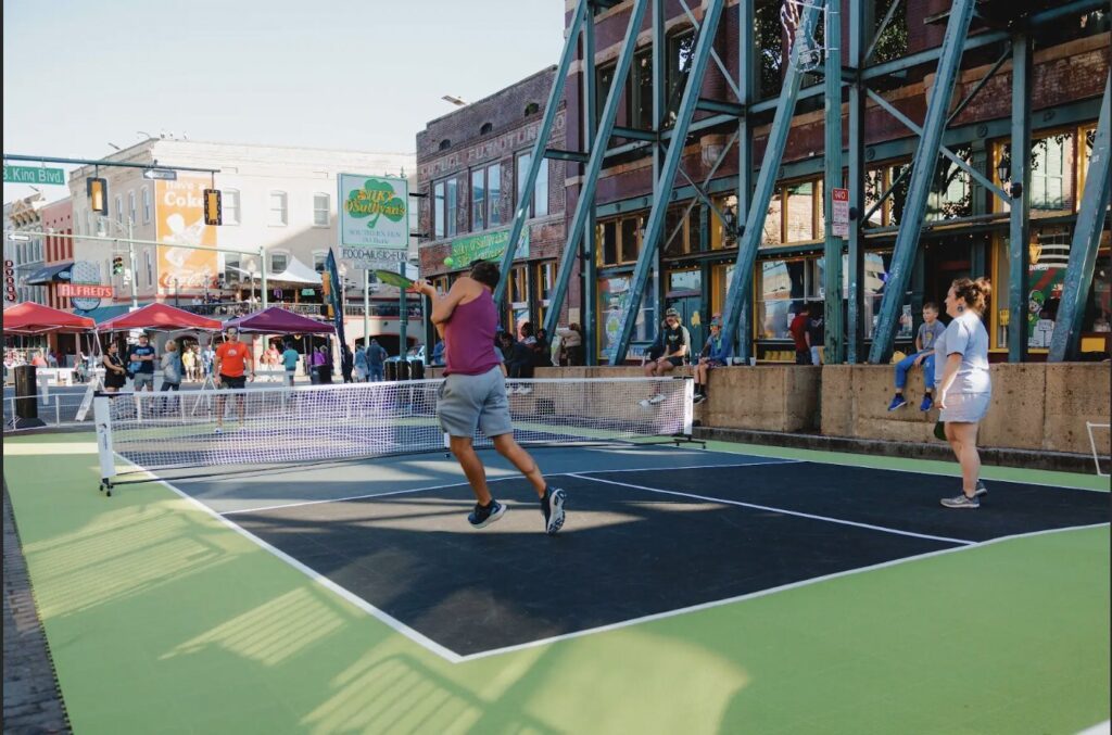 Image: A group of diverse individuals playing pickleball on a temporary court set up by Pickleball Pop-Ups, showcasing the accessibility and inclusivity of the sport.