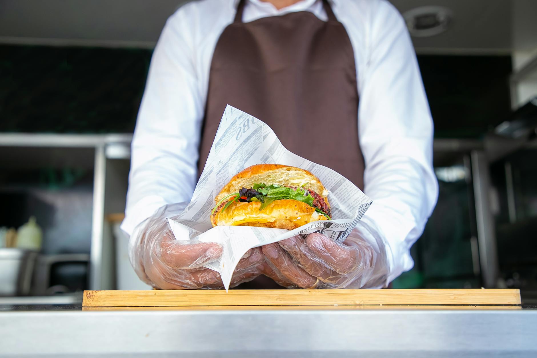 cook standing in food truck and giving burger