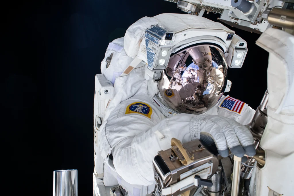 NASA astronauts Tracy C. Dyson and Matt Dominick performing a spacewalk outside the International Space Station, with Earth in the background.