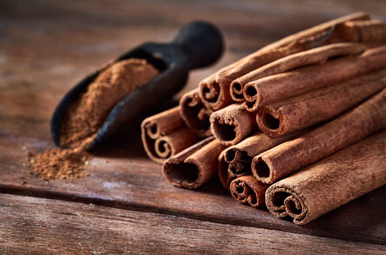 Stick cinnamon and cinnamon powder on rustic wooden table.