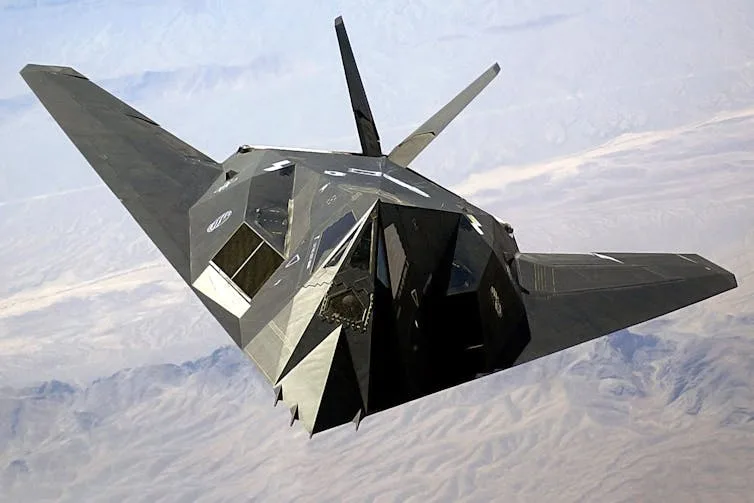 a single-seat odd-shaped jet aircraft flies high above the desert