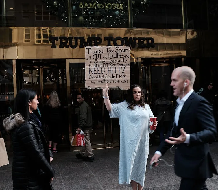 A woman in front of Trump Tower holds a sign criticizing tax cuts.