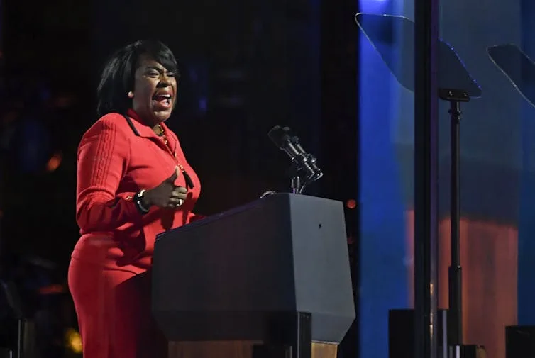 Woman in red sweater speaks at podium