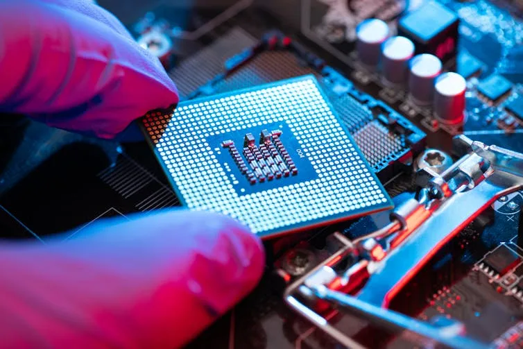 Close-up of gloved hand holding square semiconductor chip