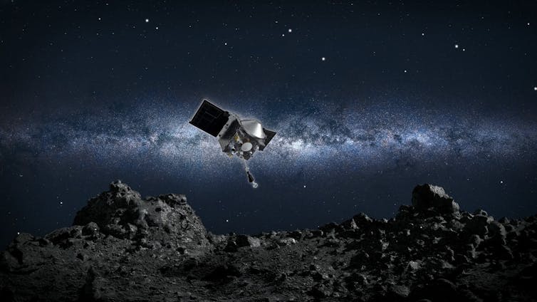 An illustration of a small spacecraft with solar panels and an extending arm hovers above an asteroid's rocky surface in space.