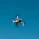 low angle shot of a white drone camera flying in the blue sky