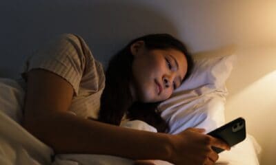 a woman lying on the bed while using her mobile phone